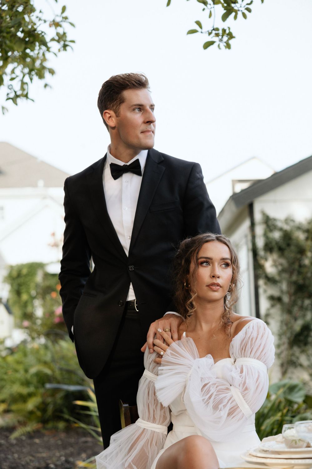 A elegant couple poses in formal wedding attire on an outdoor patio.