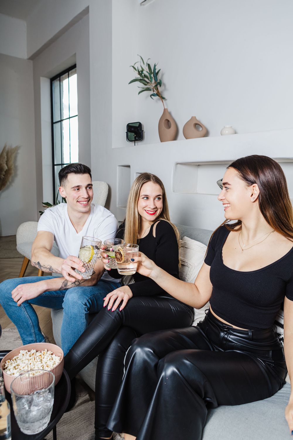 Friends raising glasses in a toast while enjoying snacks in modern living room setting.