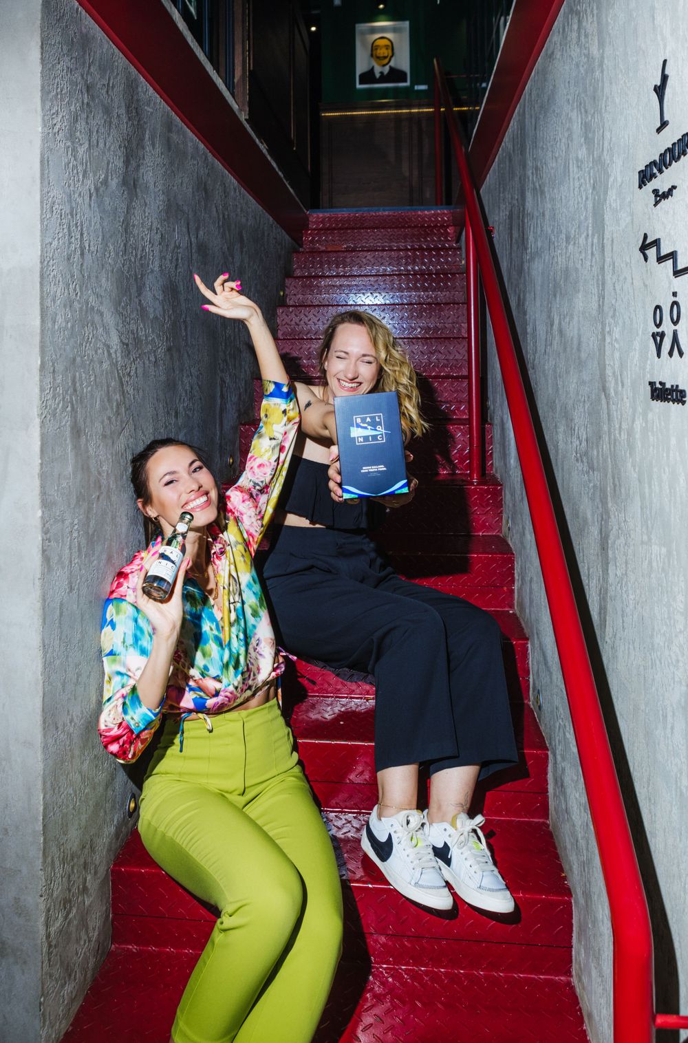 Two people sitting on red stairs showing excitement while holding passports.