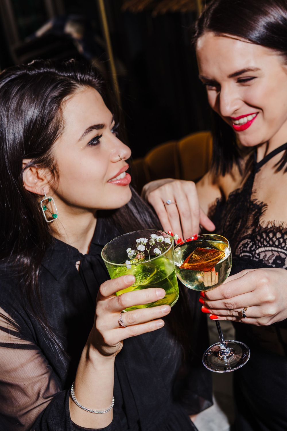 Friends sharing colorful cocktails and laughter at an elegant evening gathering.