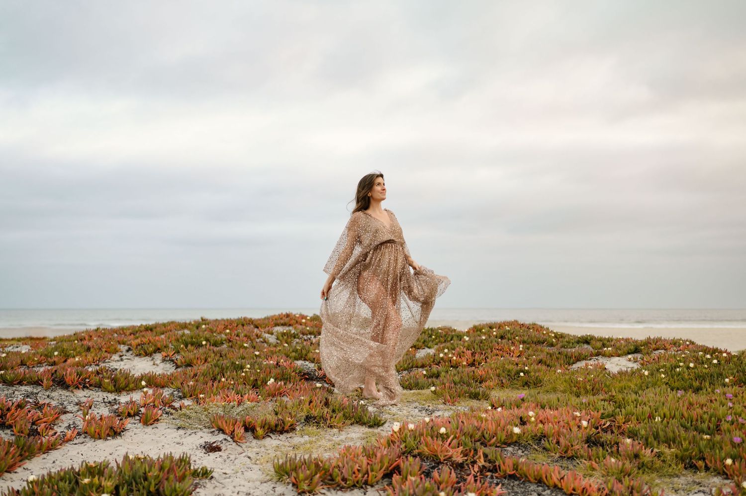 woman dancing on sand dunes in Ventura during her sunset maternity photoshoot by Santa Barbara photographer