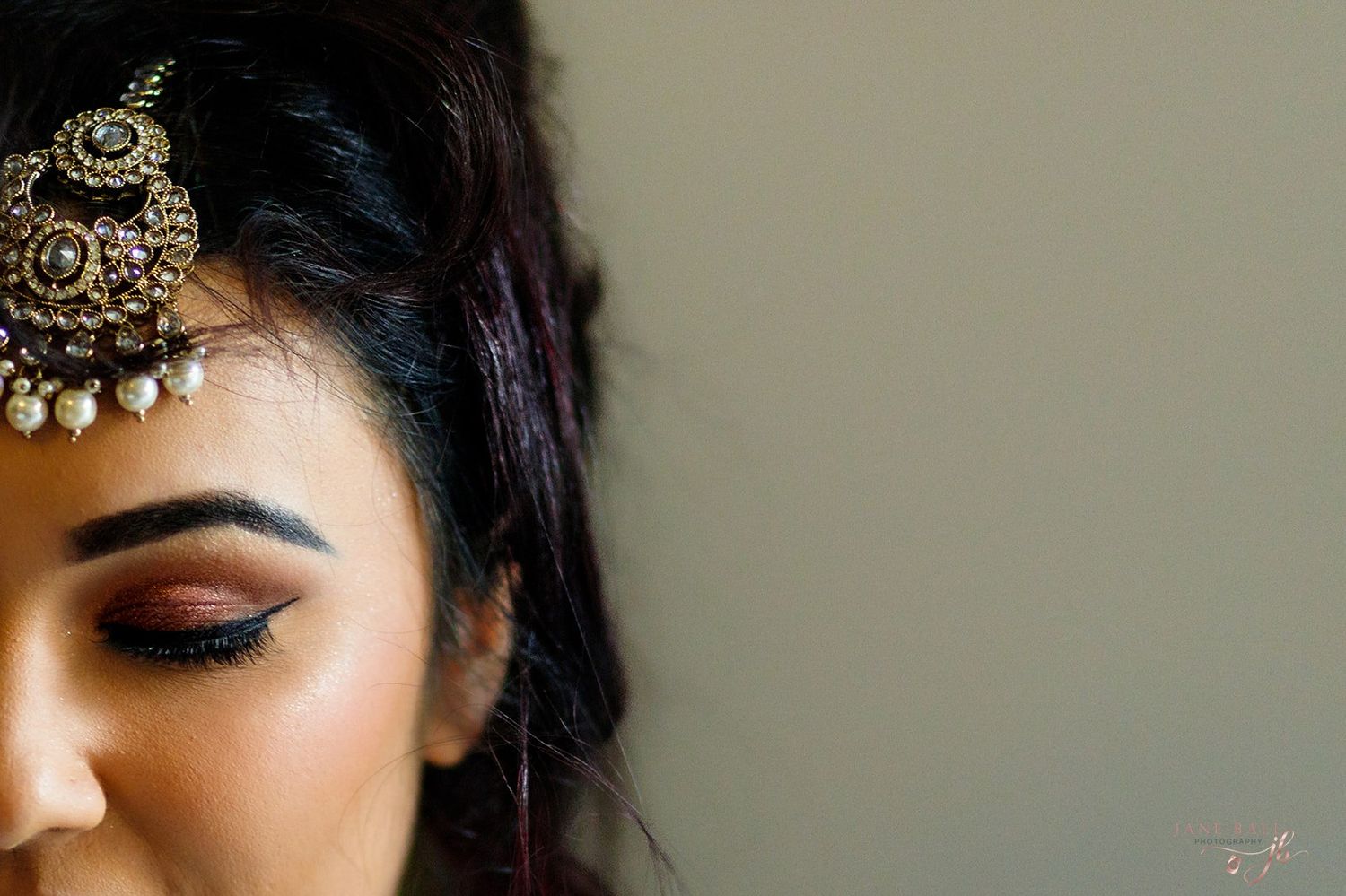Close-up beauty shot showing glittery gold eyeshadow and dramatic false eyelashes in warm lighting.