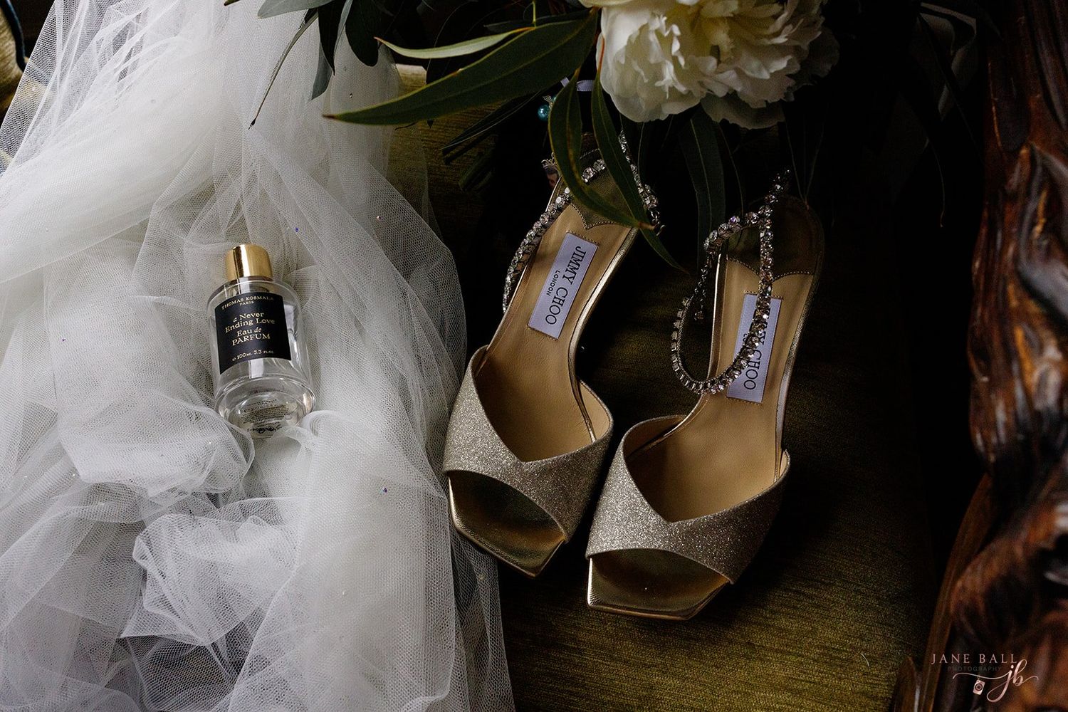 Wedding shoes and white tulle dress details arranged artistically in vintage-inspired setting.