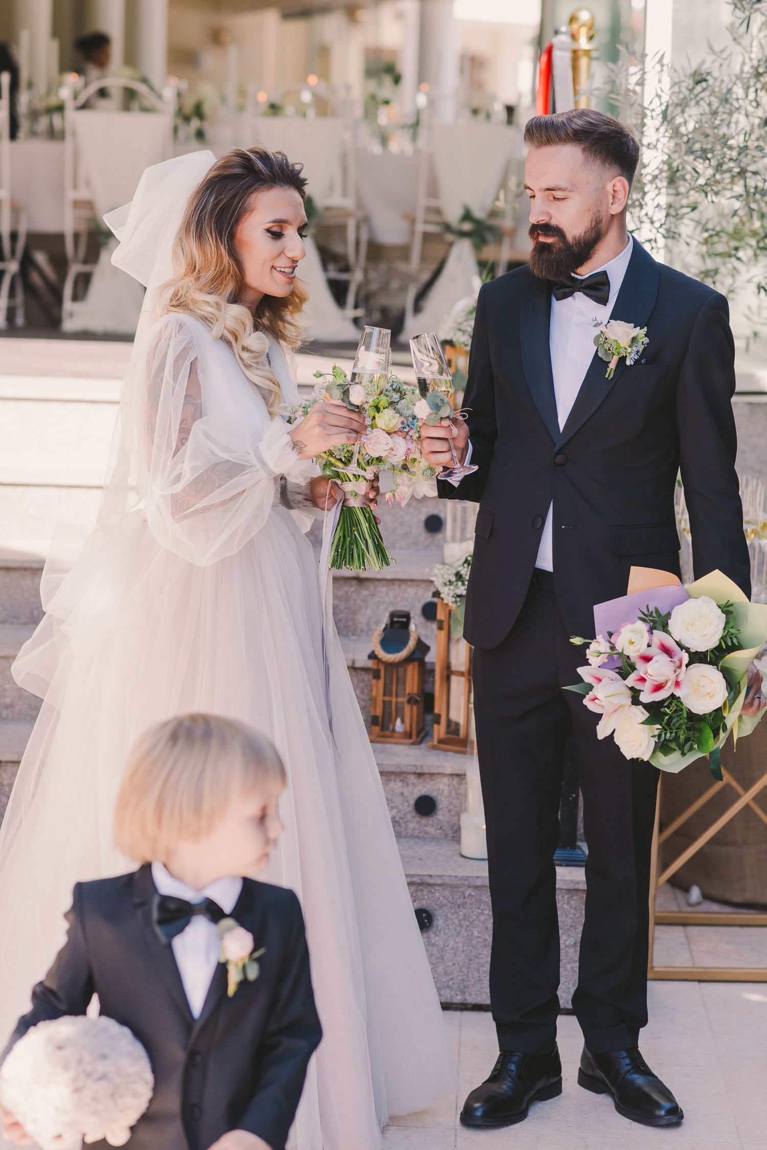 Elegant wedding scene with couple and child sharing champagne toast at decorated venue.