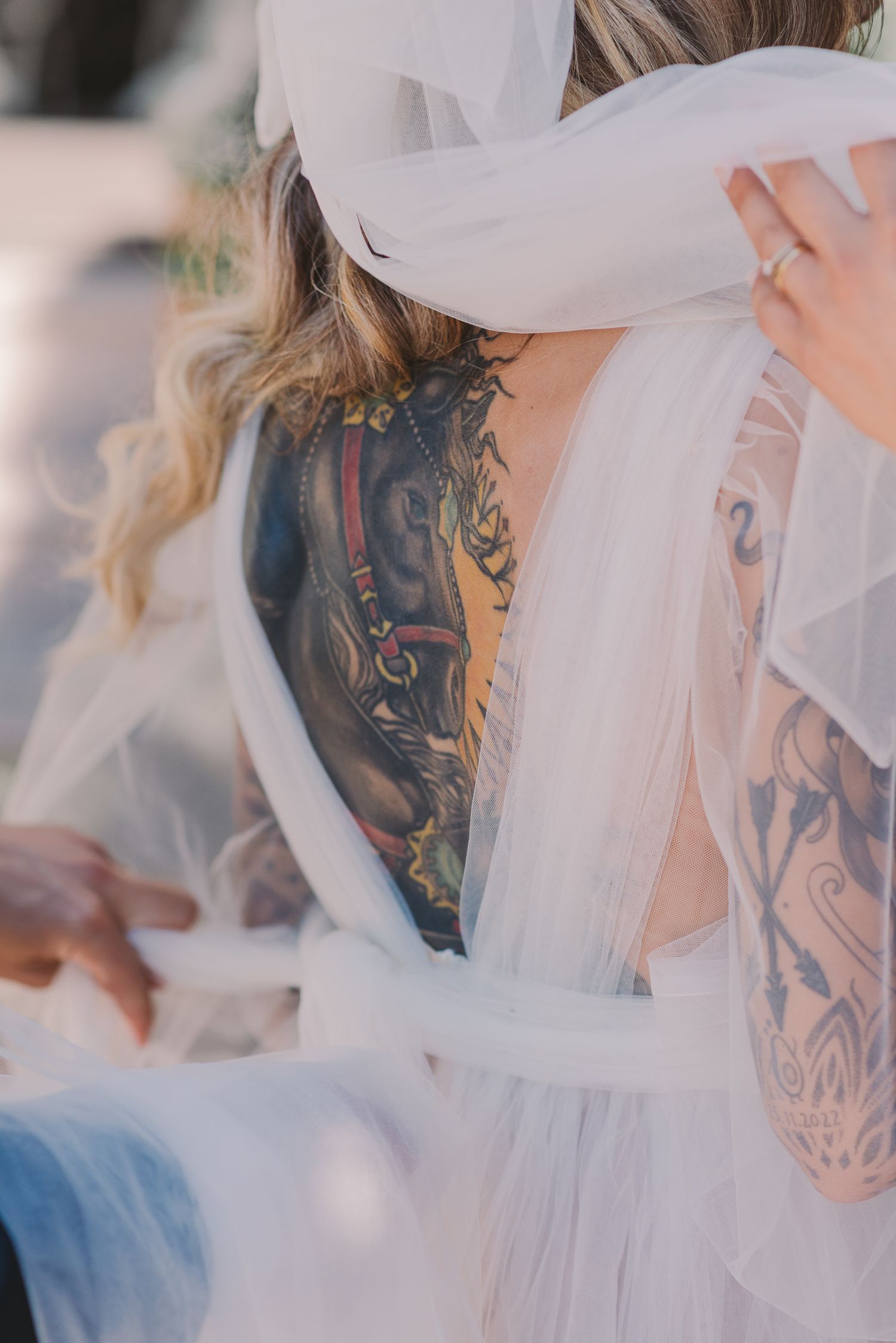 Close-up of delicate white veil and intricate tattoo artwork.