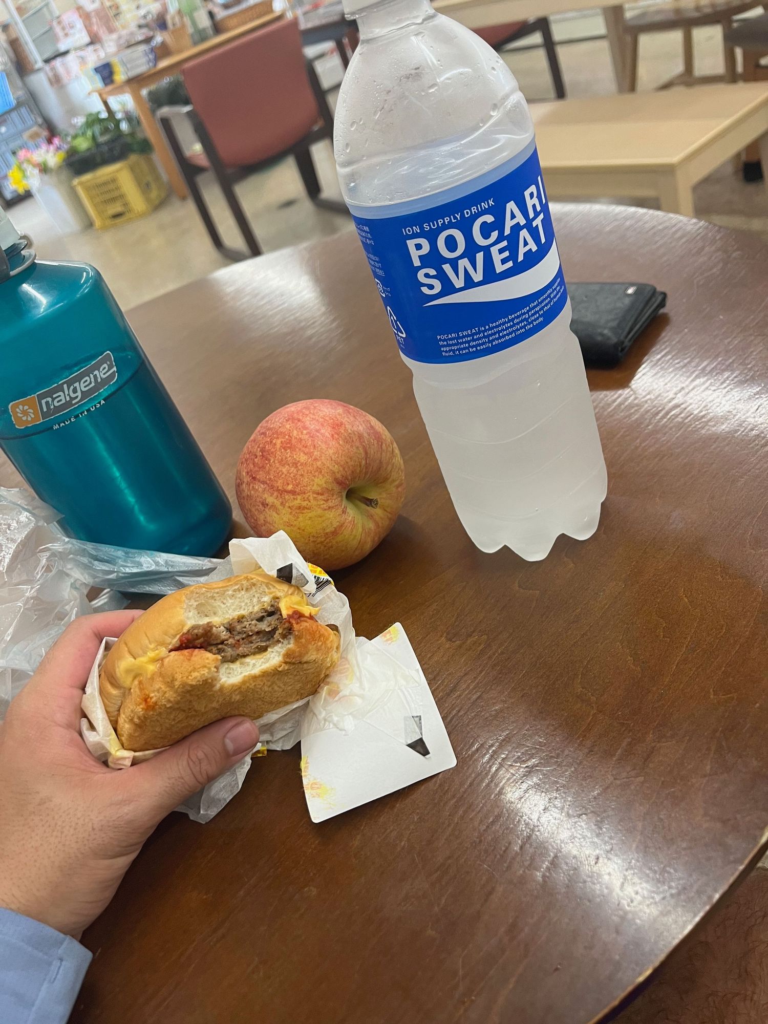 Lunch spread on wooden table with Pocari Sweat drinks and snacks.