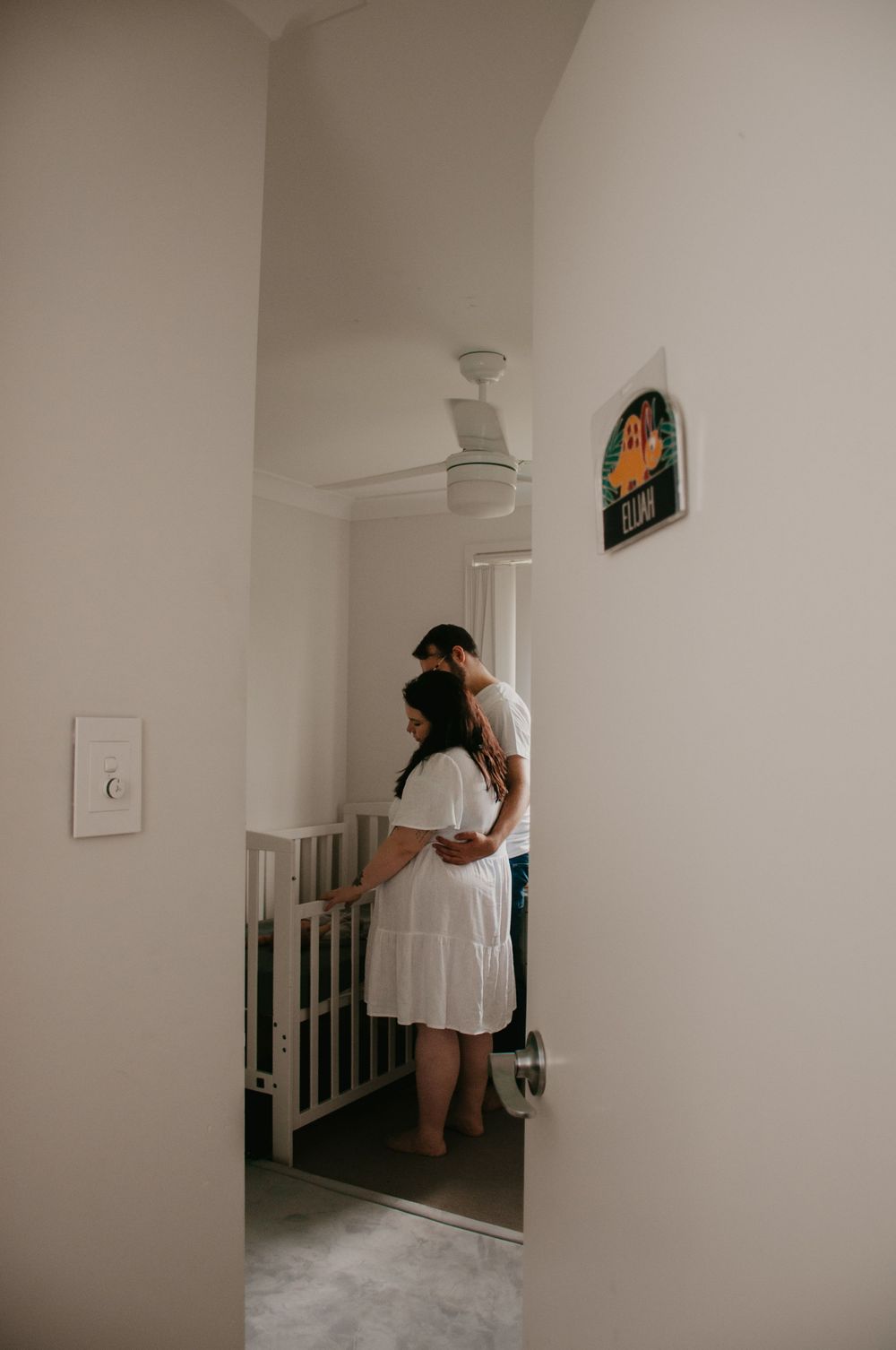 in home newborn session. mum and dad cuddling while looking into the cot