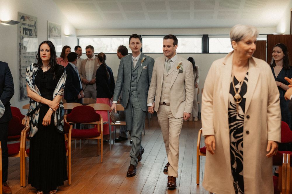 Wedding guests walking through a modern reception area with red chairs.