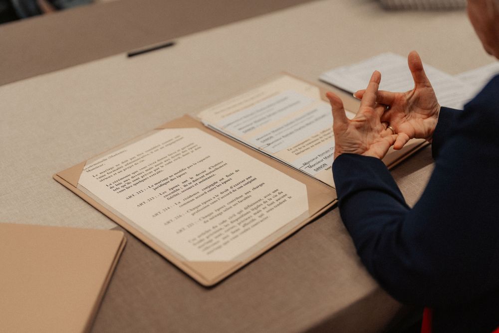 A close-up of hands gesturing over an open ceremonial book on a table.