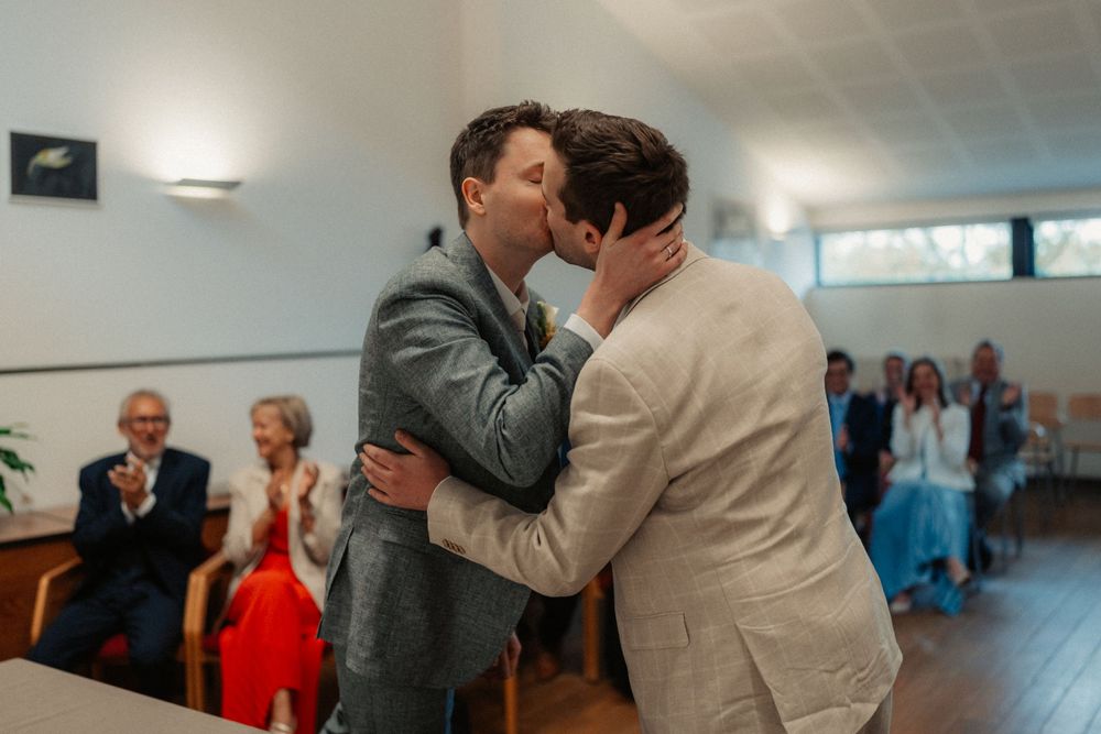 A tender moment shared between two people in suits during a wedding ceremony.