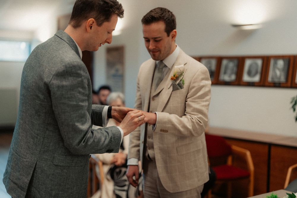 Two people in formal attire examining rings during a wedding ceremony.