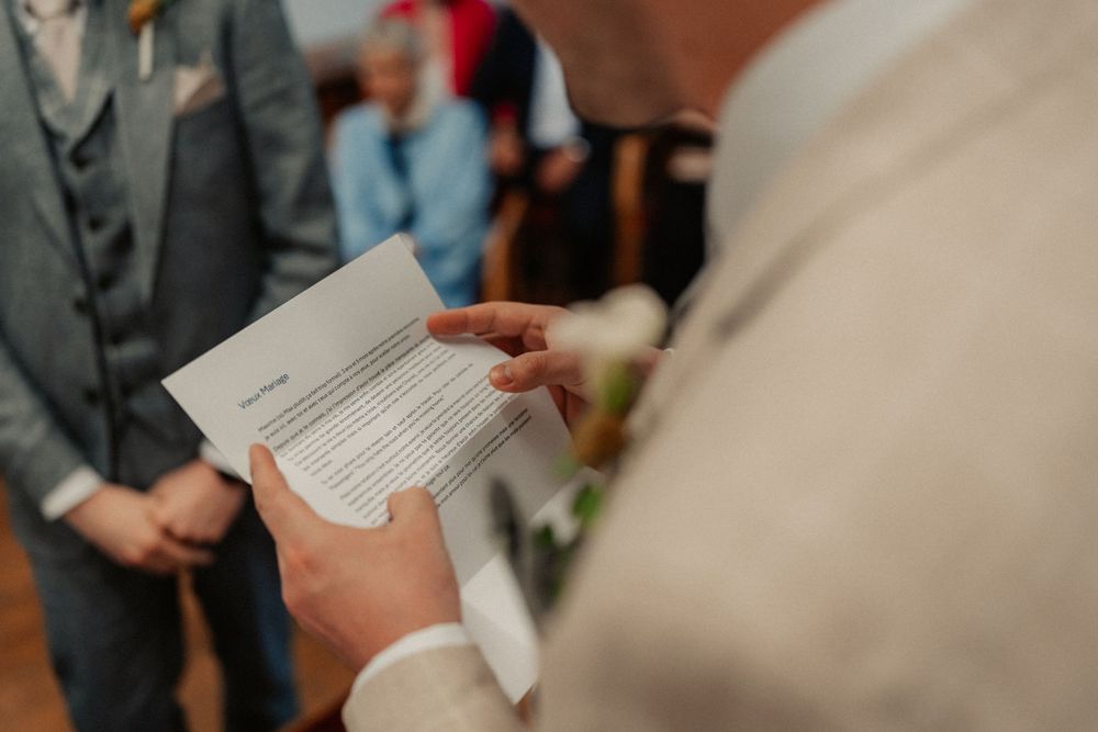 A close-up of hands holding a wedding ceremony document in an indoor setting.