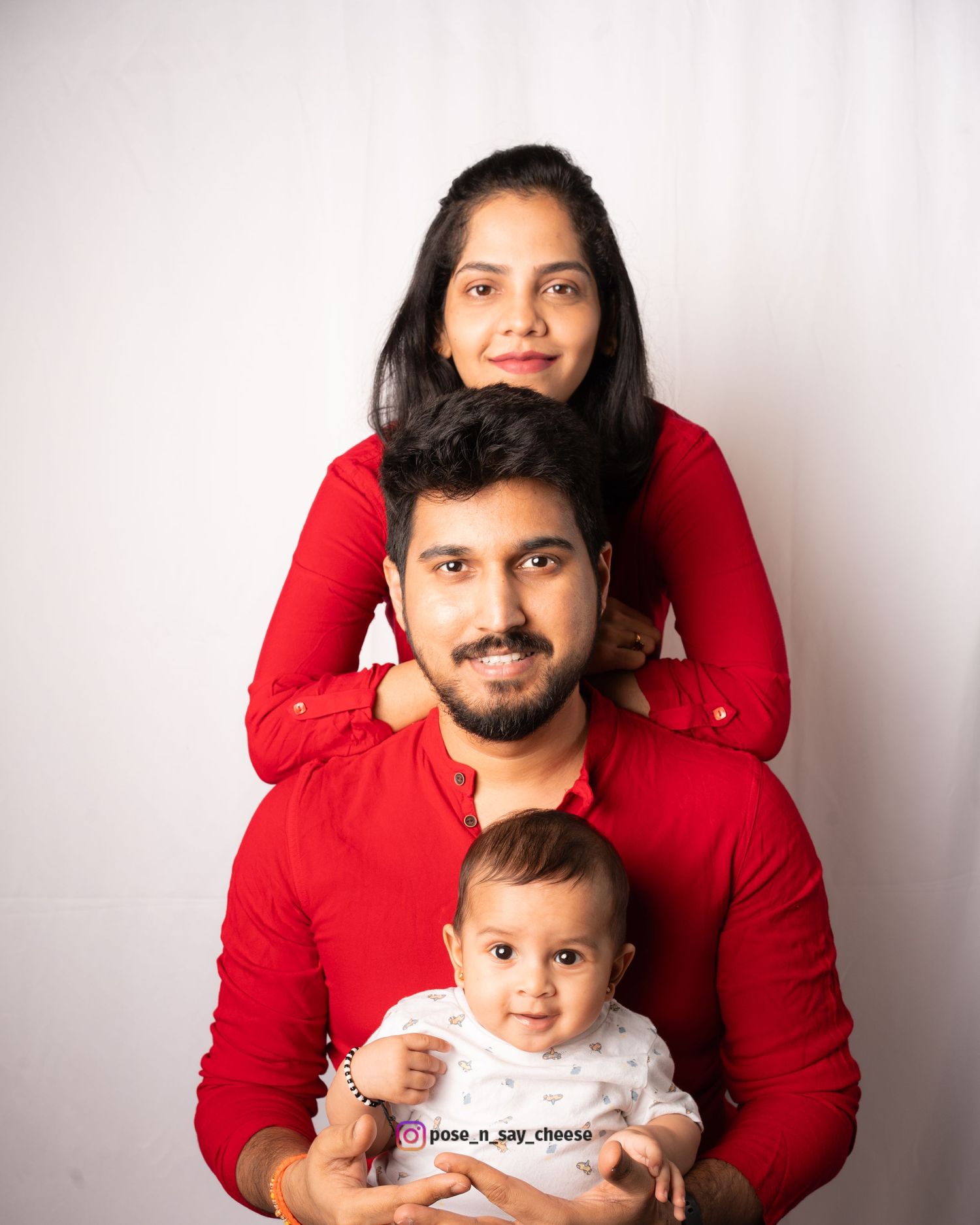 A family portrait in matching red outfits against a white background.