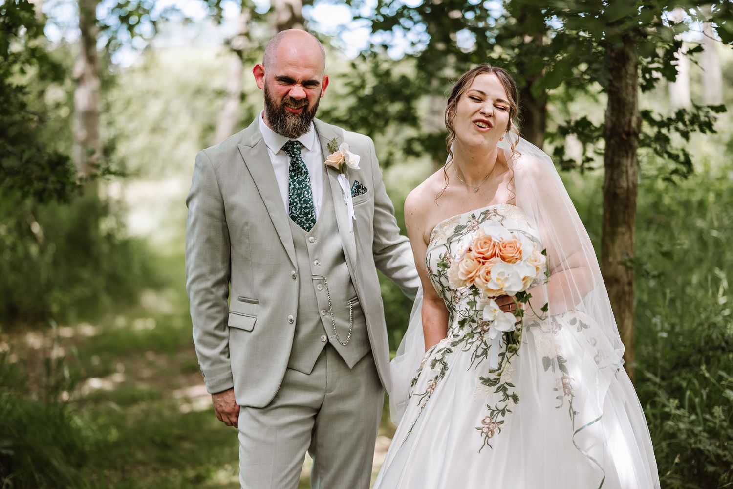 Bride and groom walking hand in hand outdoors, bride holding peach bouquet in white gown, groom in light gray suit. The Old Milking Parlour