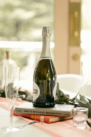 Bottle of Prosecco on a wedding table beside a book and champagne flute.