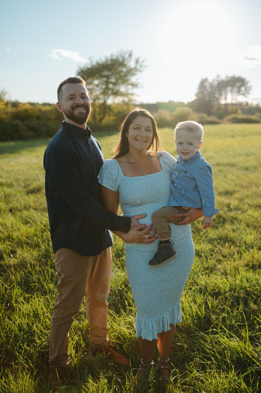A family shares joyful moments together in a sunlit field during golden hour.
