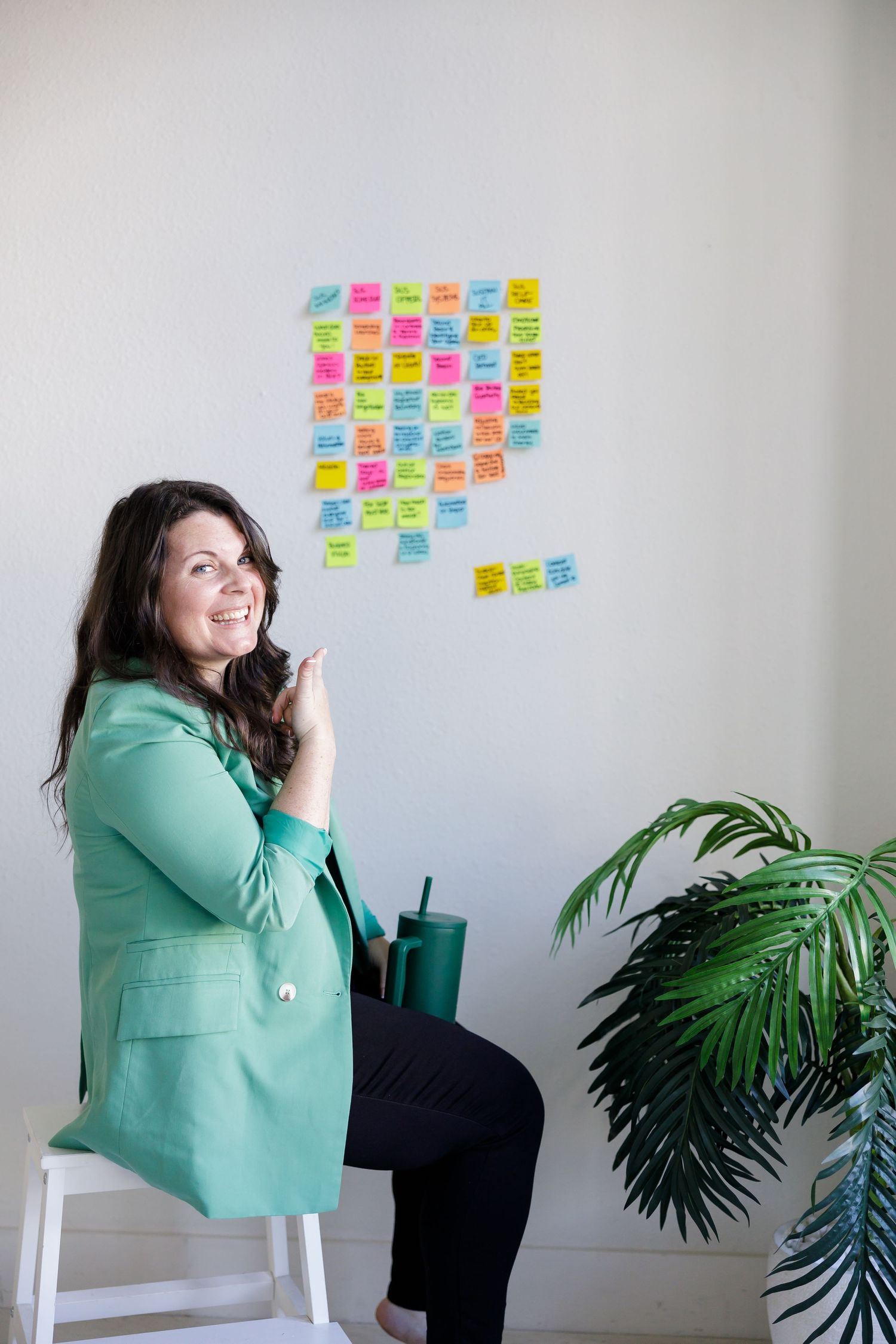 Woman burnout coach in Tacoma, WA GRLS Studio Personal branding photoshoot pointing at postit notes on wall