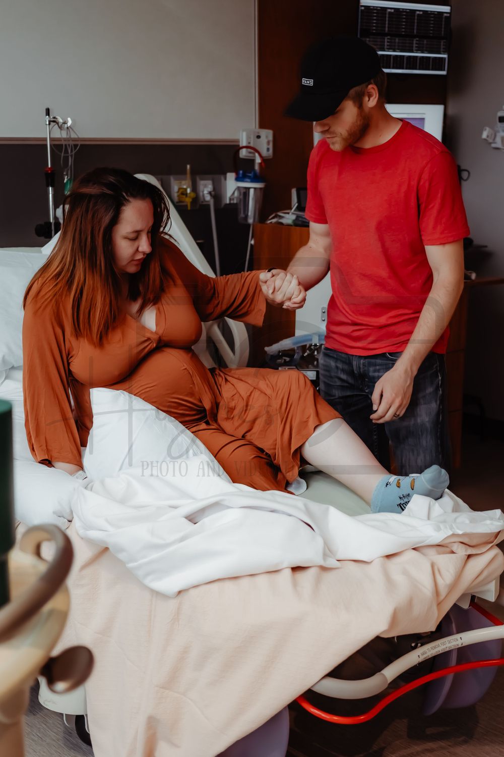 Person in orange dress receives medical care while sitting on a hospital bed.