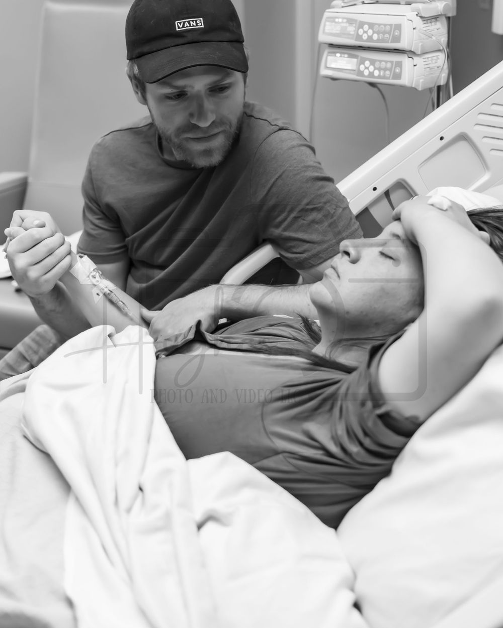 Medical care being provided in a hospital room with monitoring equipment visible.