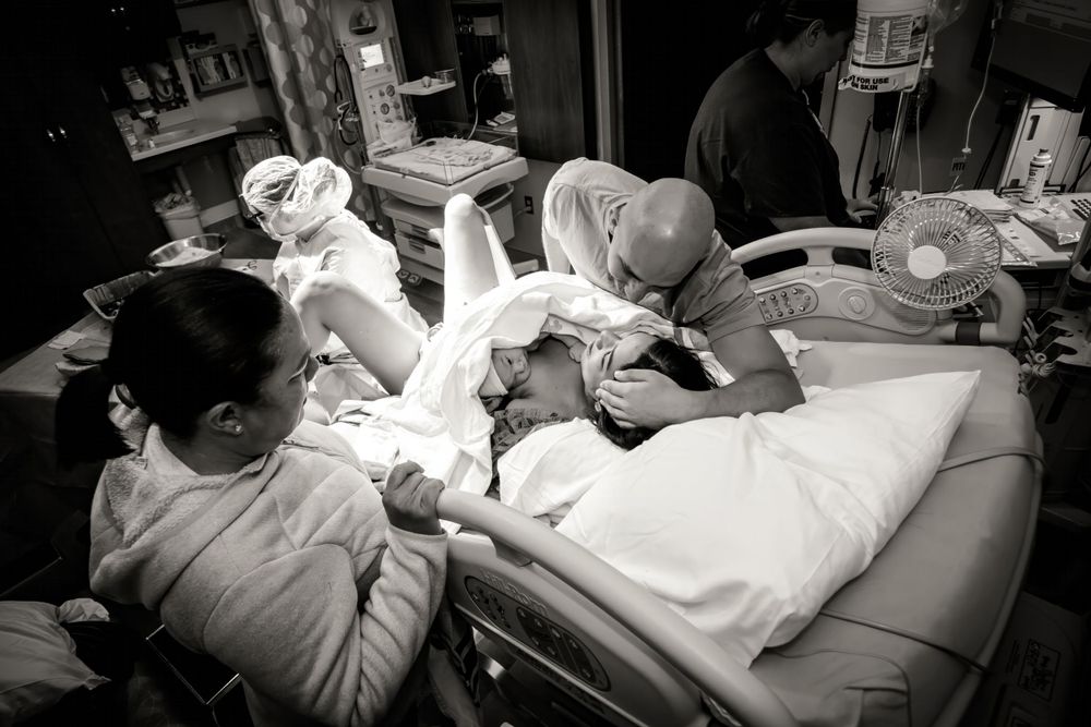 Healthcare providers assisting with delivery in black and white medical scene.