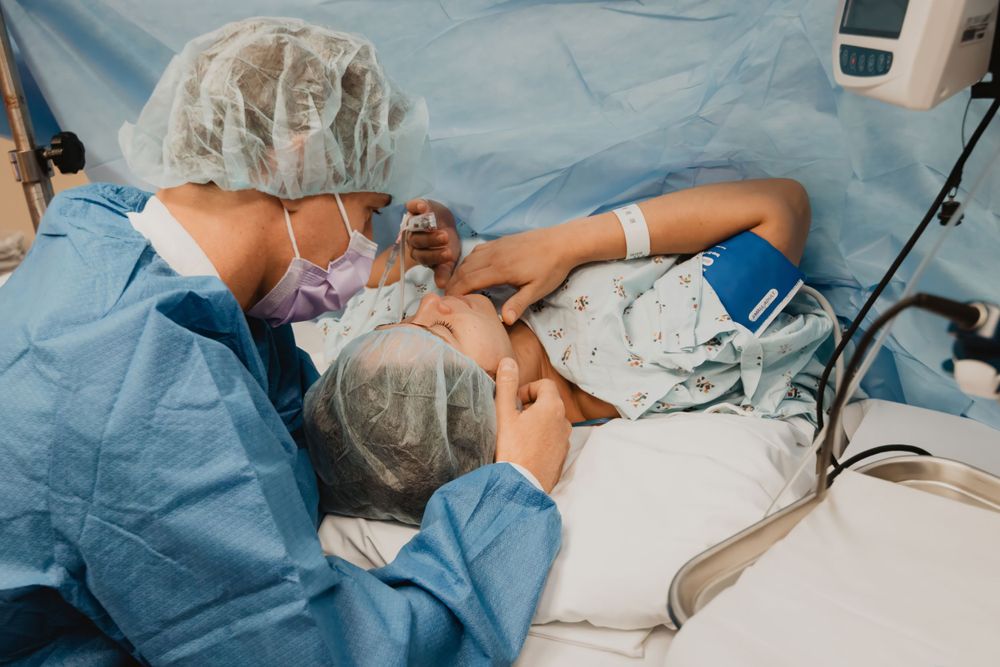 Healthcare provider in scrubs and protective equipment providing medical care.