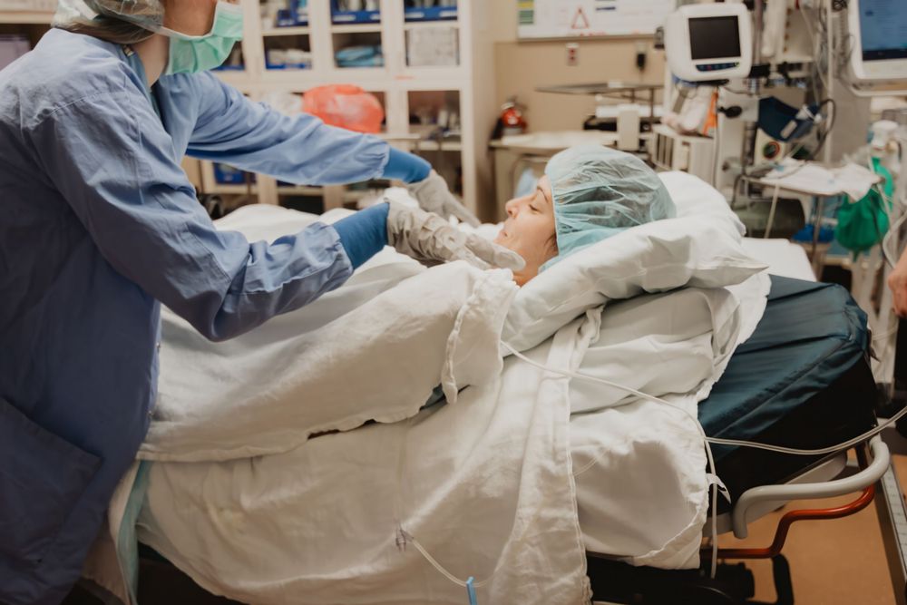 Healthcare professionals performing medical care in hospital room with equipment.