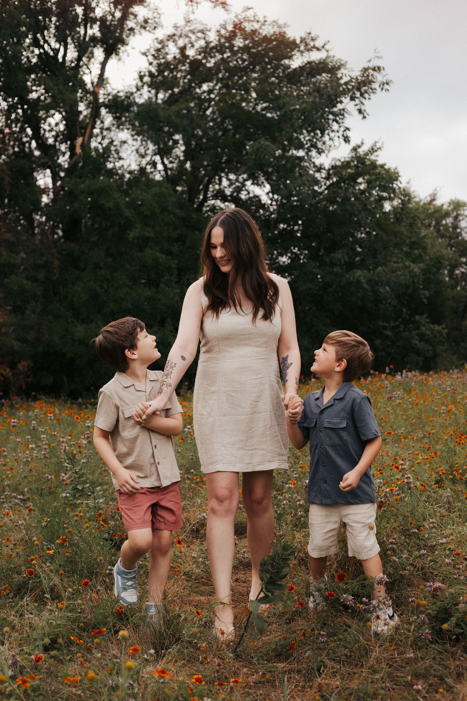 A tender outdoor family portrait amidst wildflowers and trees.
