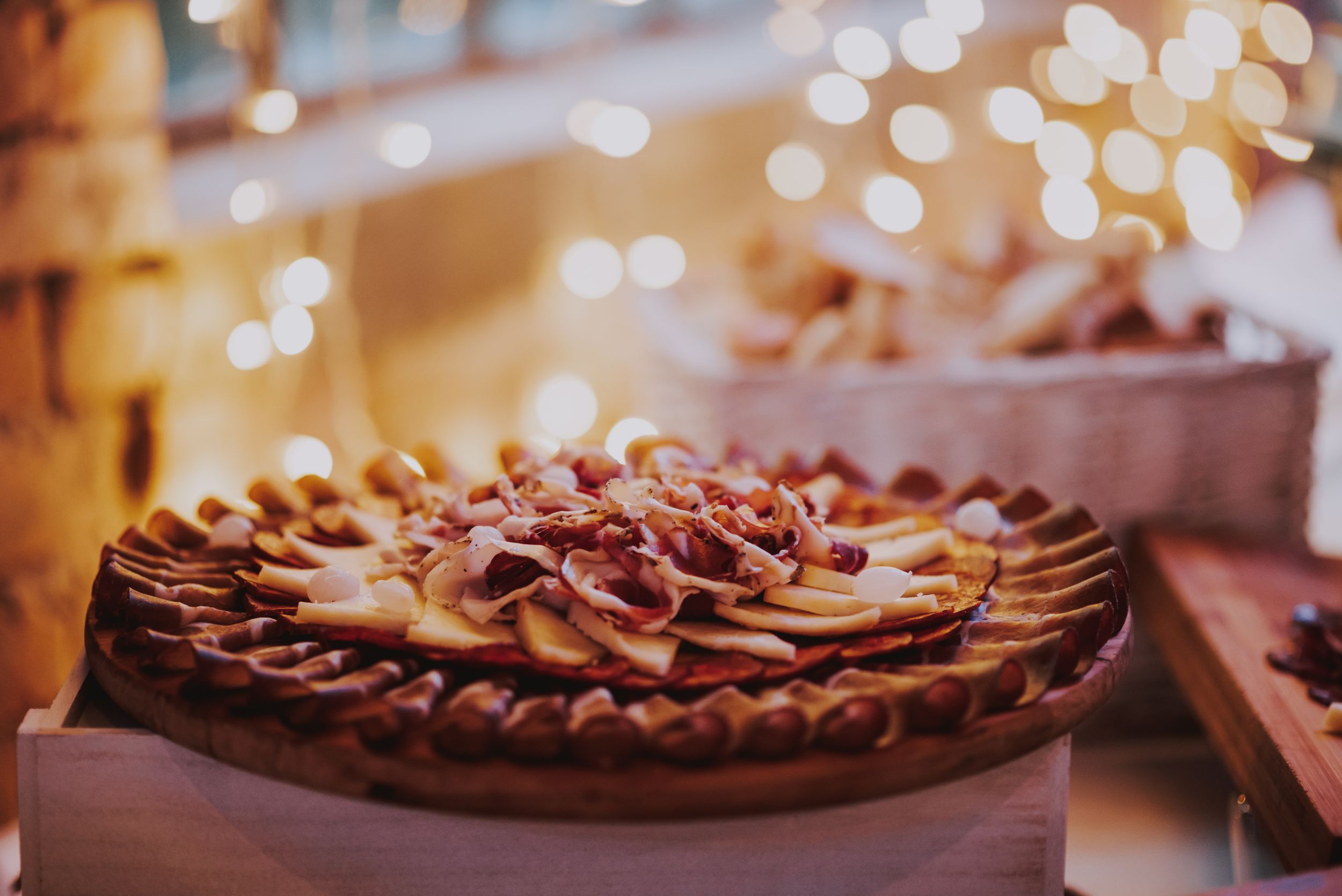 Close-up of ornately decorated pie with twisted pastry top and bokeh lights in background.