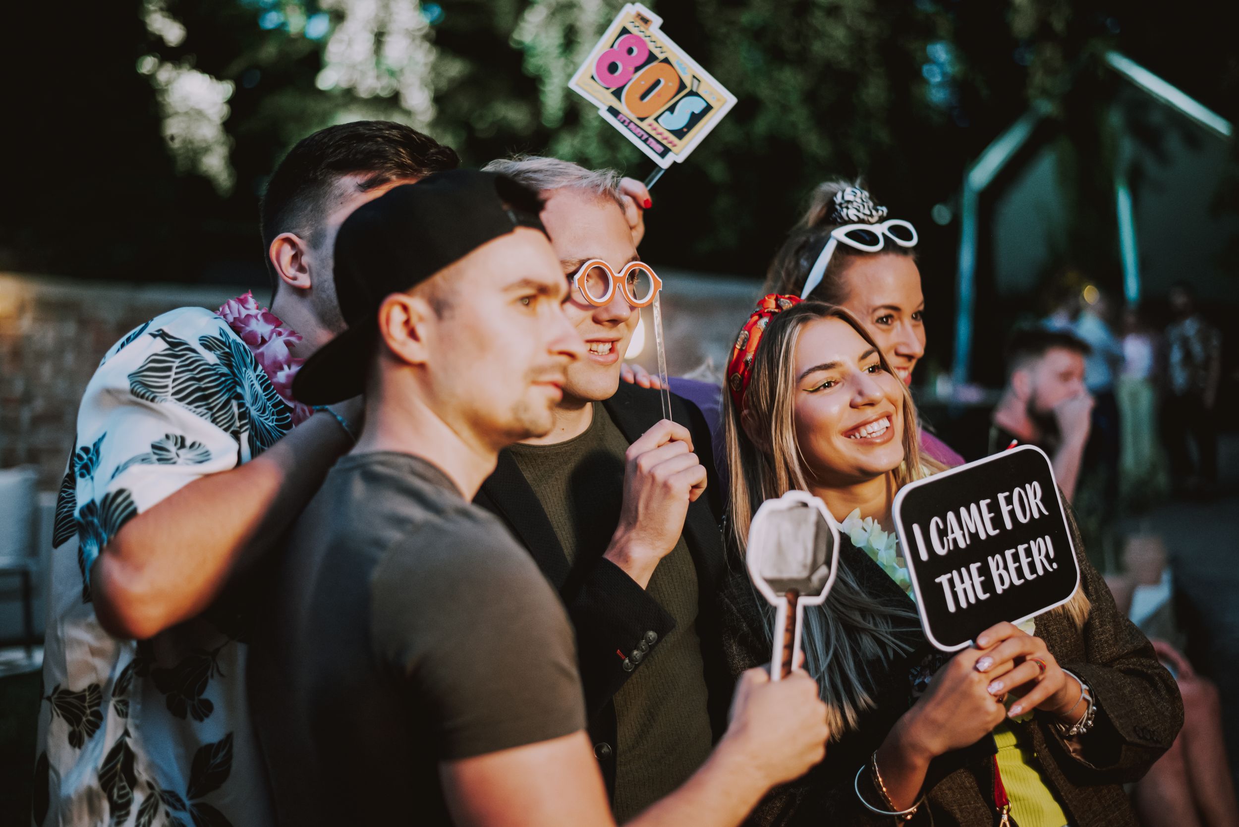 Party guests pose with fun photo props during an evening celebration.