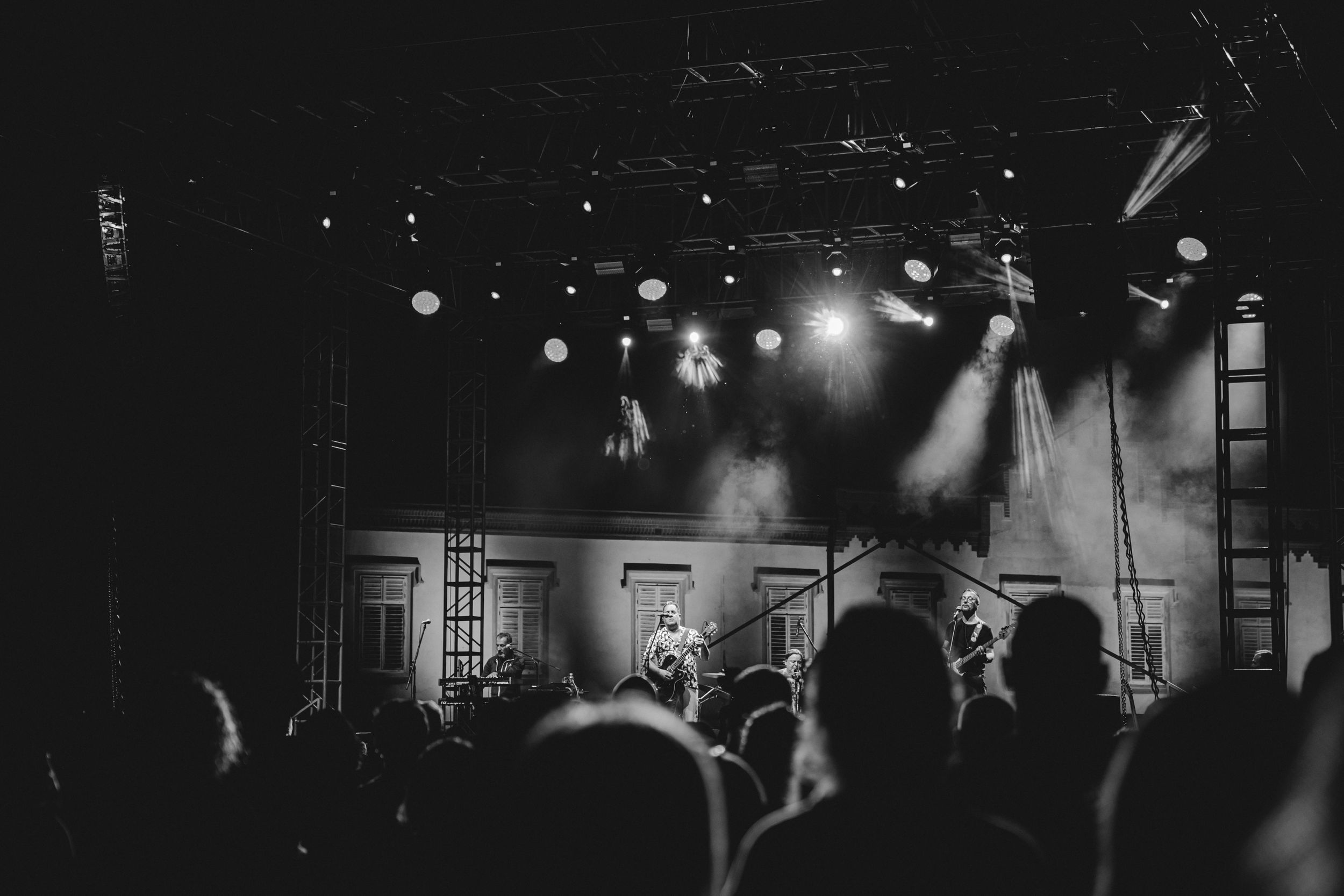 Black and white concert photo showing crowd silhouettes against bright stage lighting.