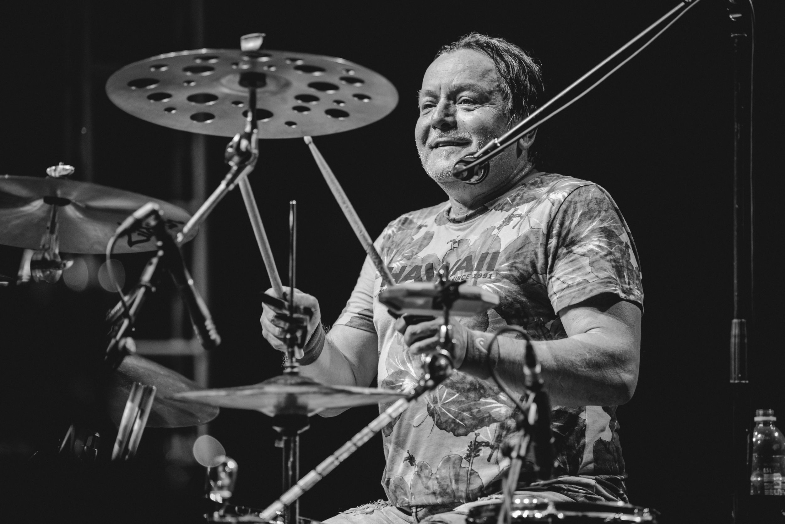 Black and white image of a drummer playing with intensity during a live performance.