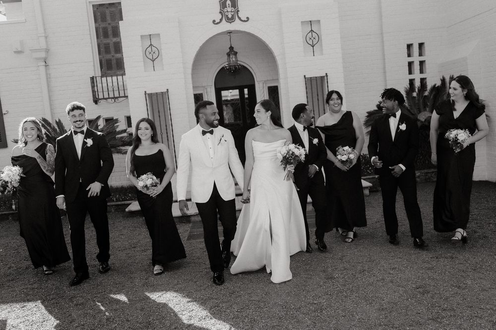 Wedding party poses in a fun running motion down a hallway in black and white photography.