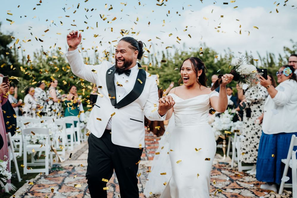 Wedding couple walks down aisle while confetti falls during outdoor ceremony celebration. Markovina Wedding - Auckland Wedding Photographer