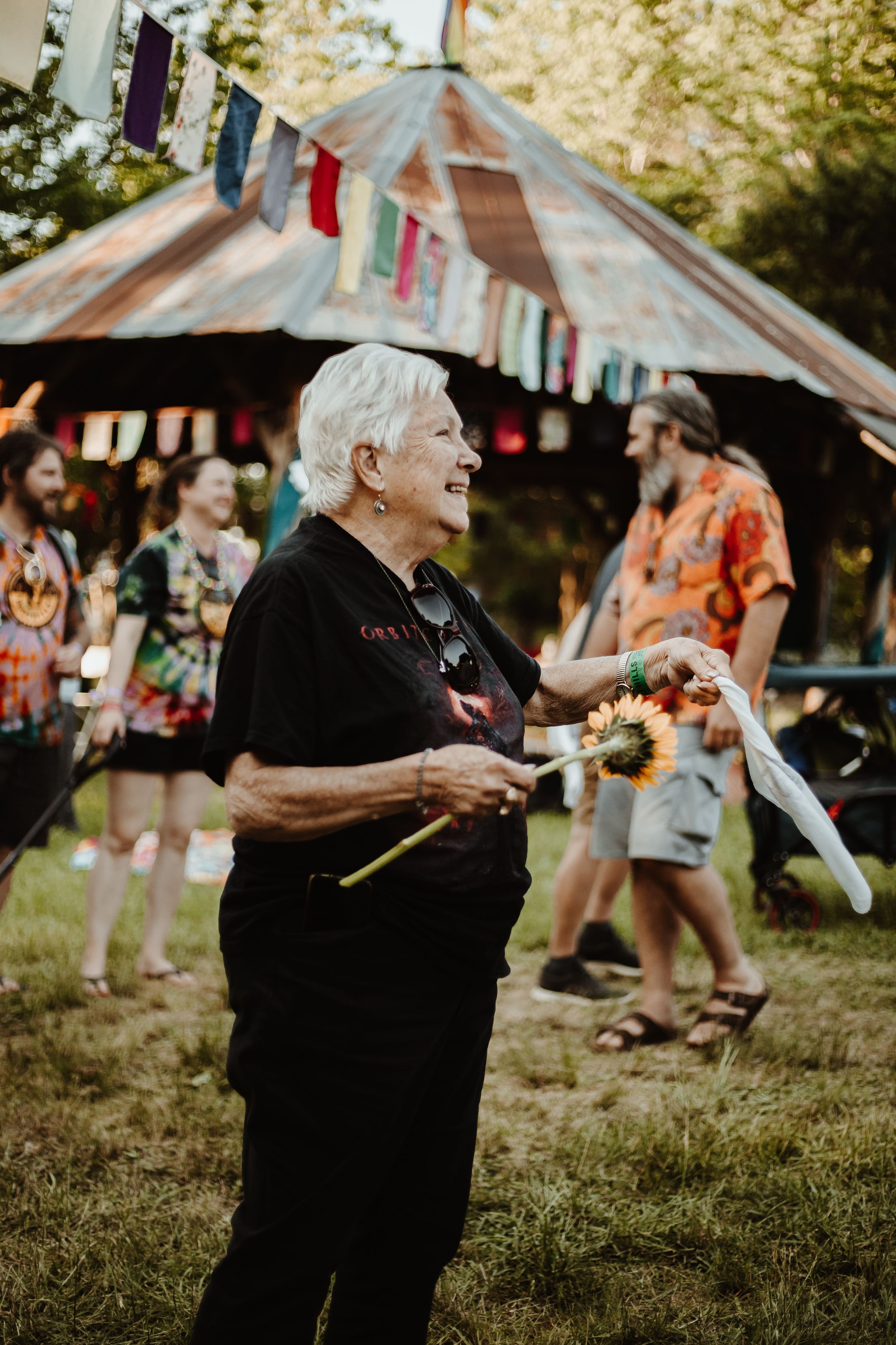 Person in black attire at outdoor festival with colorful banners and decorations.