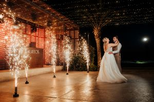 Sparklers illuminate a romantic dance floor scene with brick walls and dramatic lighting at a wedding reception.
