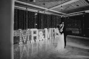 A wedding reception venue decorated with glowing light-up letters spelling 'MR & MRS' against a dark background.