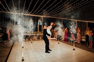 Couples dancing under a canopy of twinkling string lights at an indoor wedding reception venue.