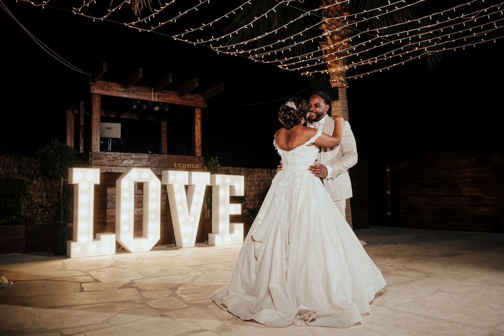 A romantic wedding reception scene with illuminated LOVE letters and string lights creating a magical atmosphere.