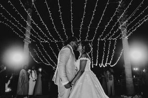 A wedding reception at night with string lights creating a magical canopy over the outdoor dance floor and celebration.