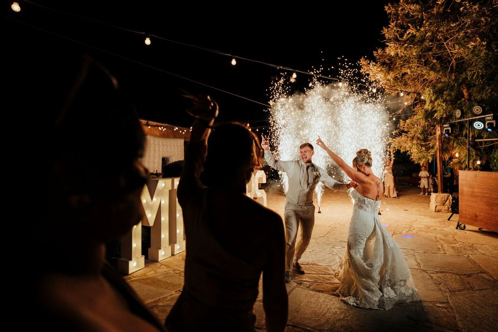 Wedding party walking down a rustic path at sunset with warm golden lighting creating a romantic atmosphere.