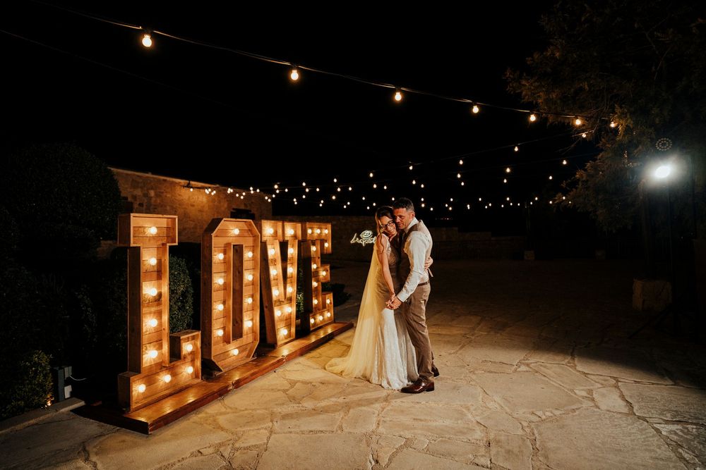 Illuminated LOVE marquee letters create a romantic backdrop for a nighttime outdoor celebration.