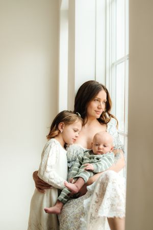 Intimate family moment captured by window in soft natural light.