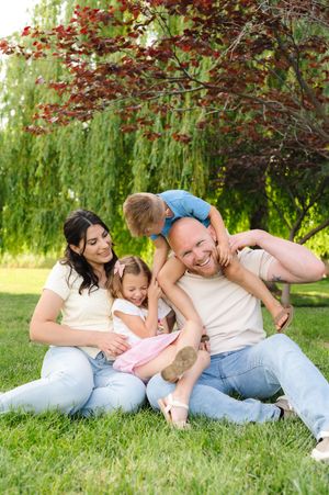 A playful outdoor family scene under blooming trees with red berries in springtime.