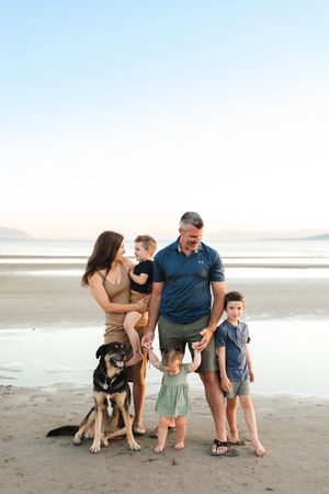 Group portrait of a family with their German Shepherd pet on a peaceful beach.