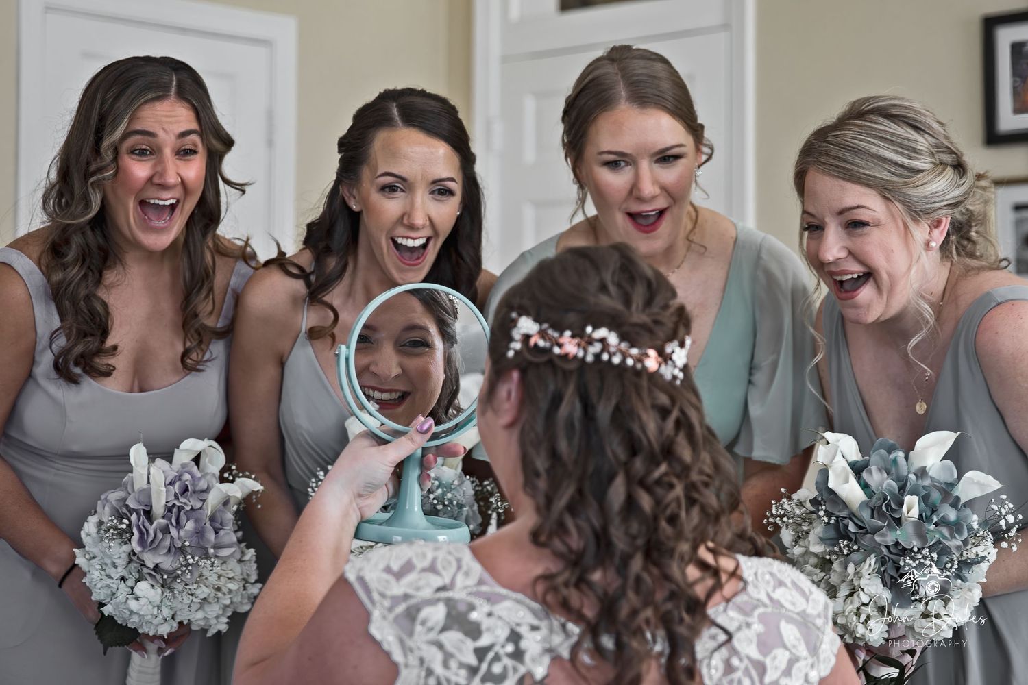 Bridesmaids in matching dresses react with excitement during wedding preparation.