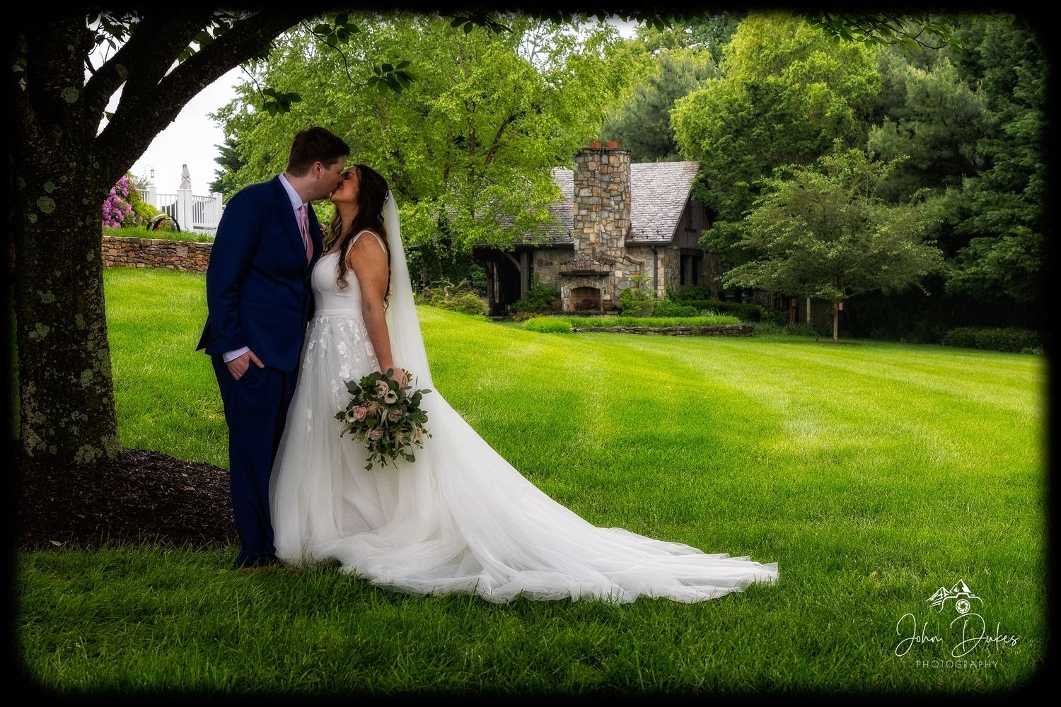 Wedding party poses for outdoor photos on a lush green lawn.