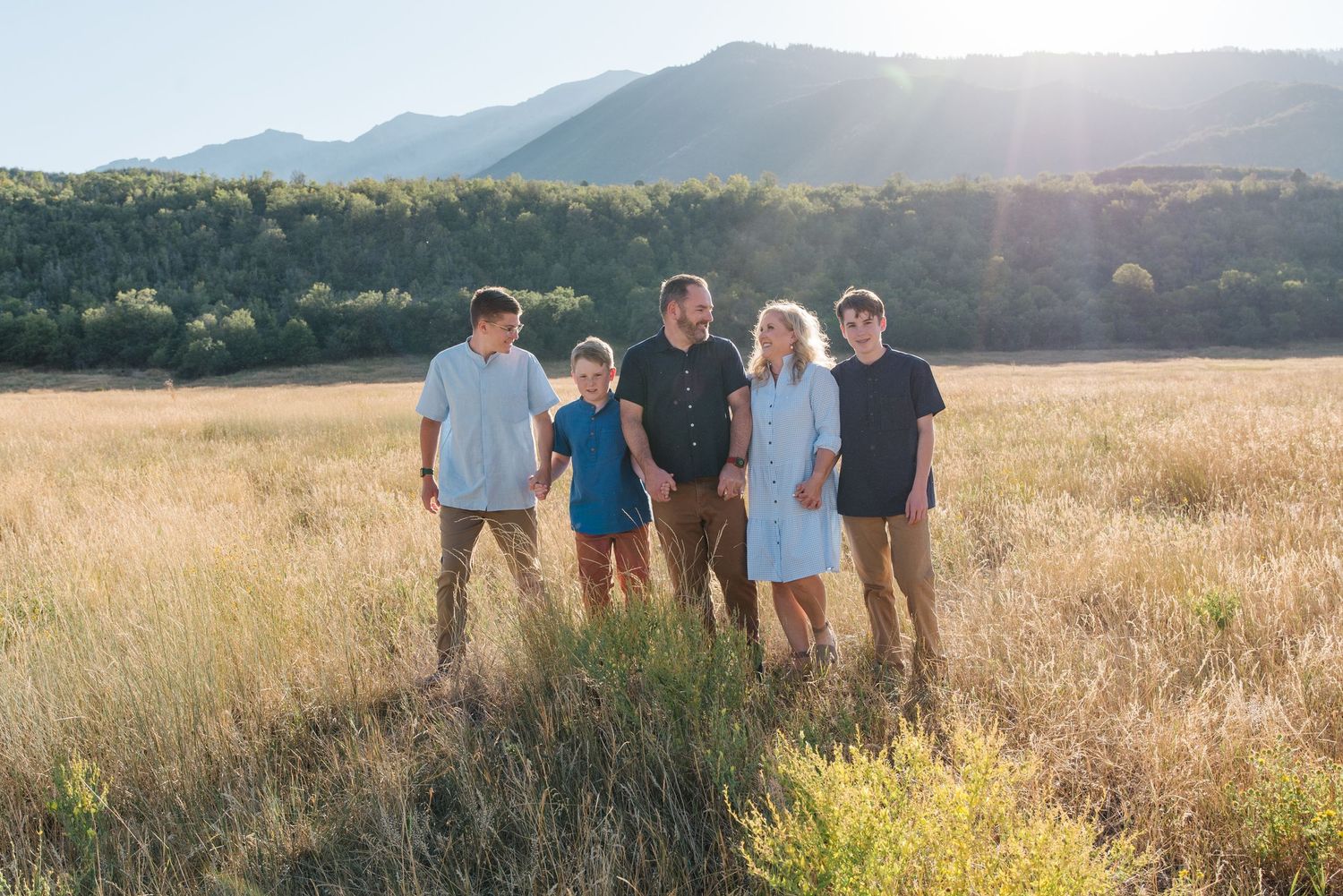 Group posing together in field with mountains and setting sun in background.
