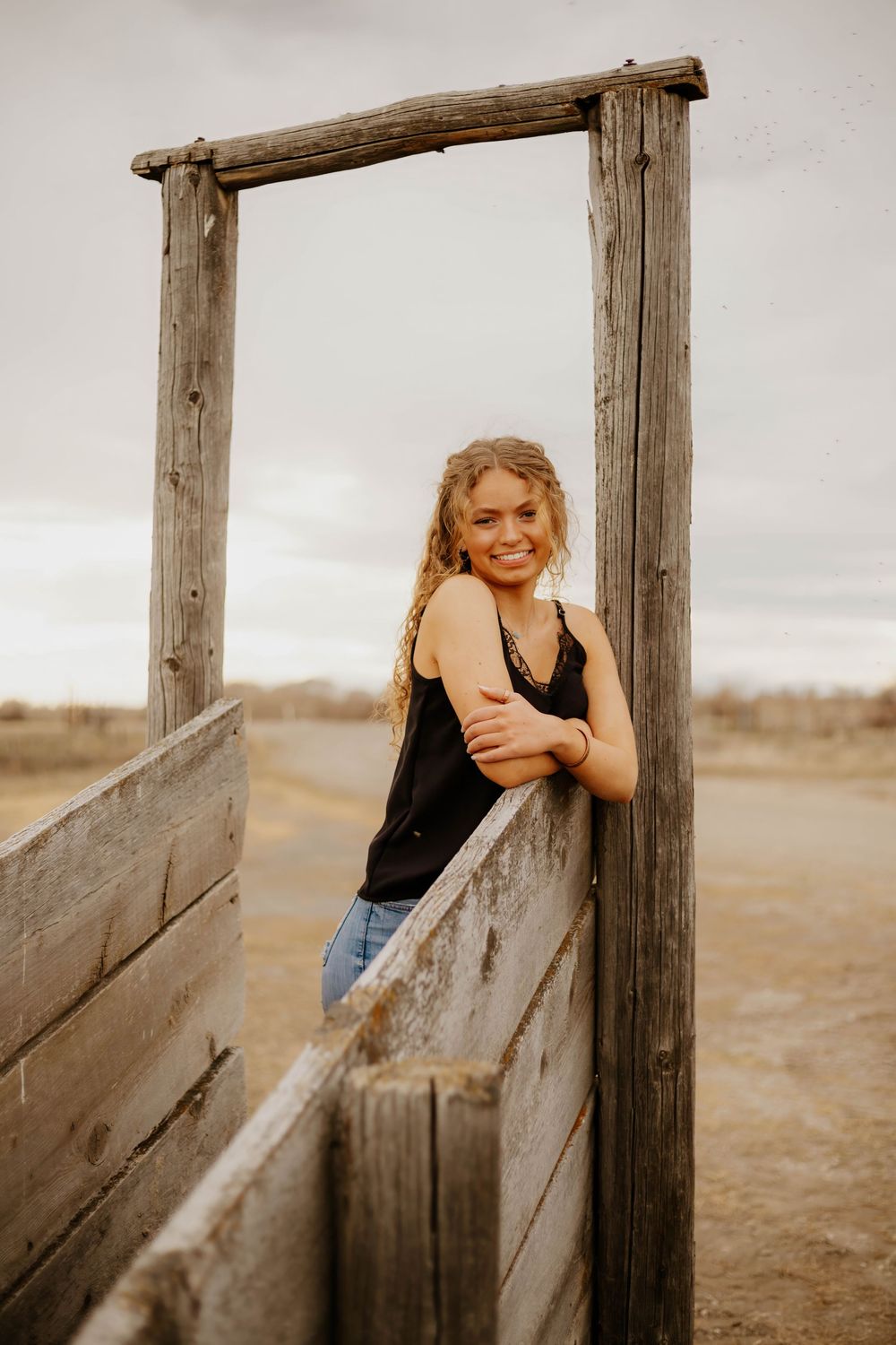 Playful poses against western weathered wooden fence posts in a rural field.