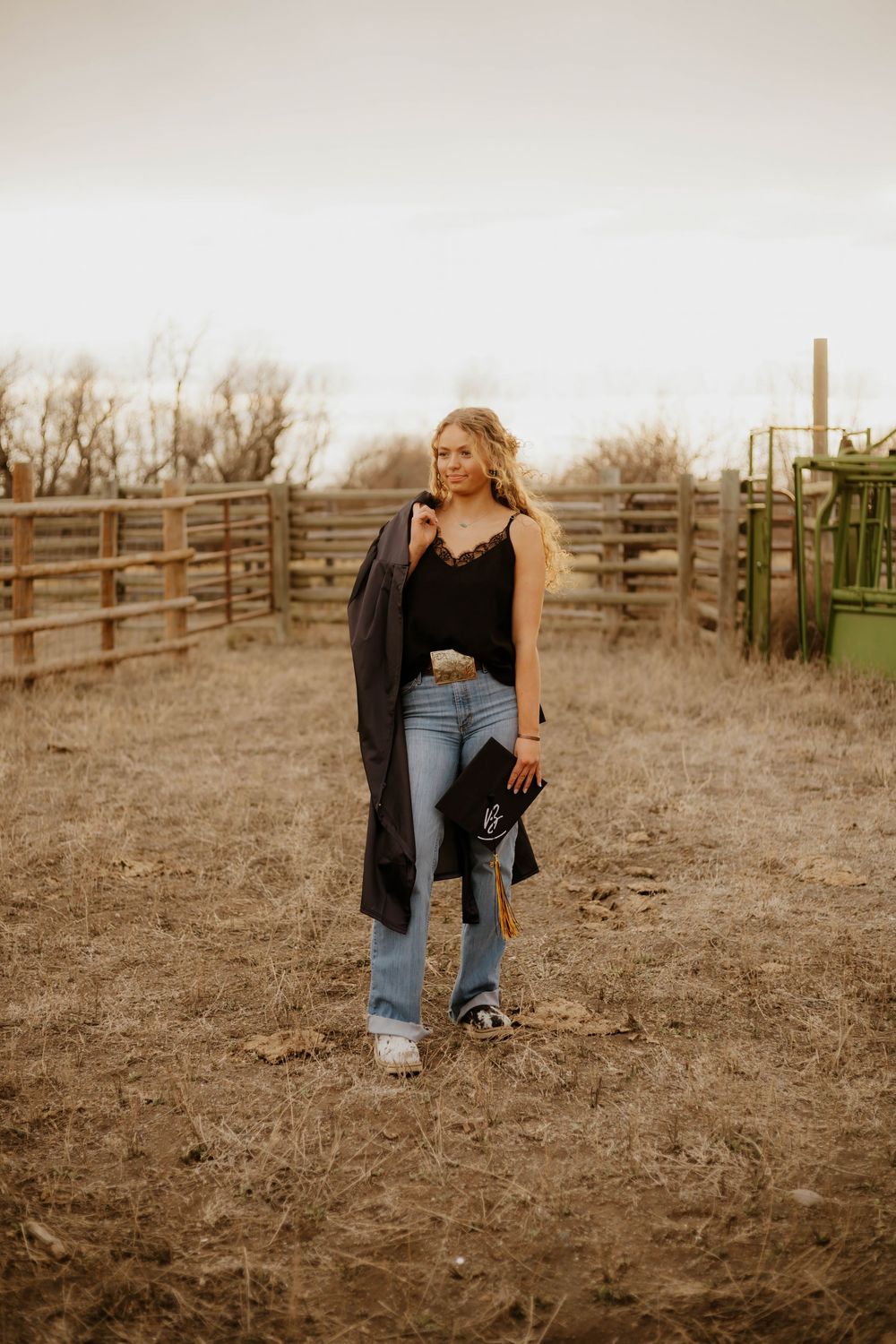 Casual western poses near wooden ranch fencing during a golden hour photoshoot.