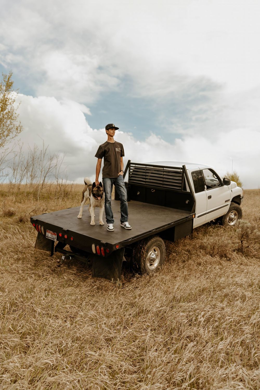 Western Person sitting on the flatbed of a white pickup truck in desert terrain.